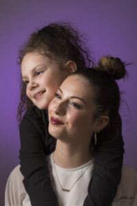 Portrait studio en couleur de deux sœurs sur fond violet.