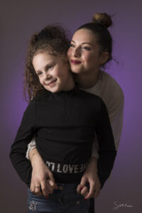 Portrait studio en couleur de deux sœurs sur fond violet.